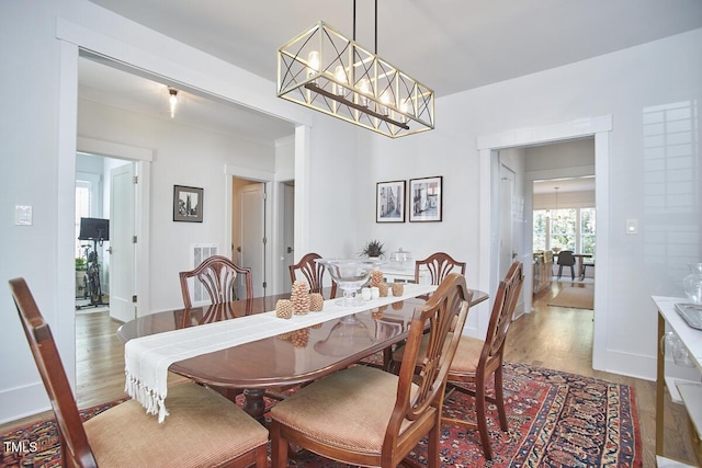 dining space featuring baseboards, a notable chandelier, and wood finished floors