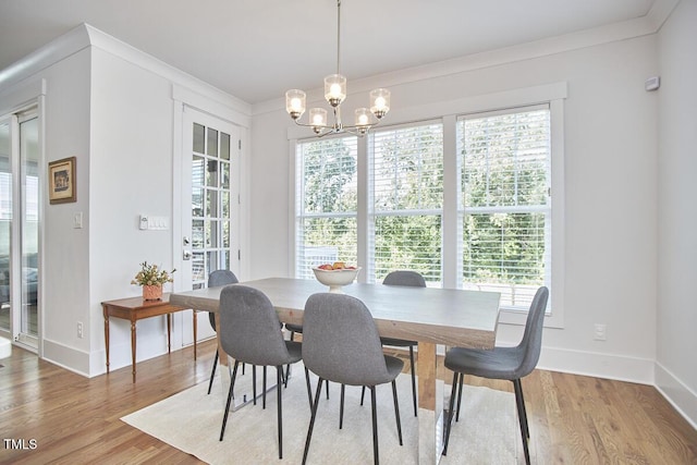 dining space featuring light wood-style flooring, crown molding, a chandelier, and a wealth of natural light