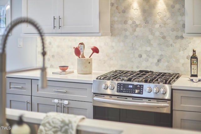 kitchen featuring decorative backsplash, stainless steel range with gas cooktop, and gray cabinetry