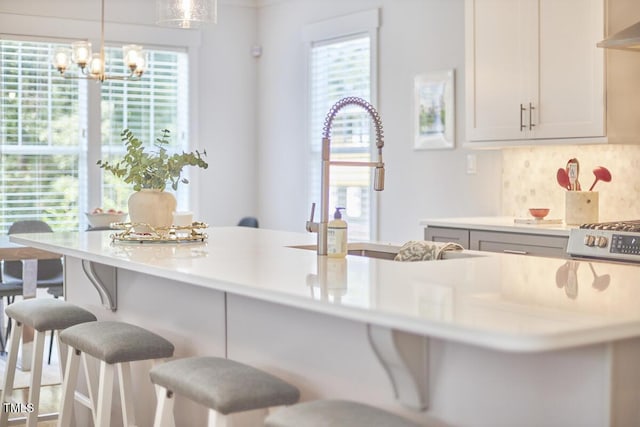 kitchen featuring plenty of natural light, a breakfast bar area, ventilation hood, and backsplash