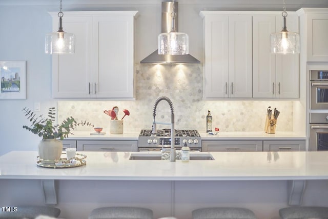 kitchen with a kitchen breakfast bar, decorative light fixtures, stainless steel oven, and wall chimney exhaust hood