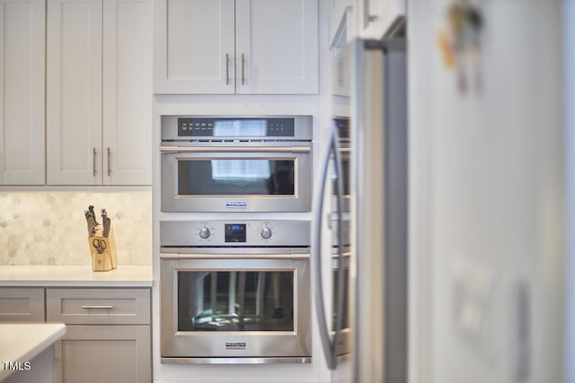 kitchen with stainless steel appliances, backsplash, and light countertops