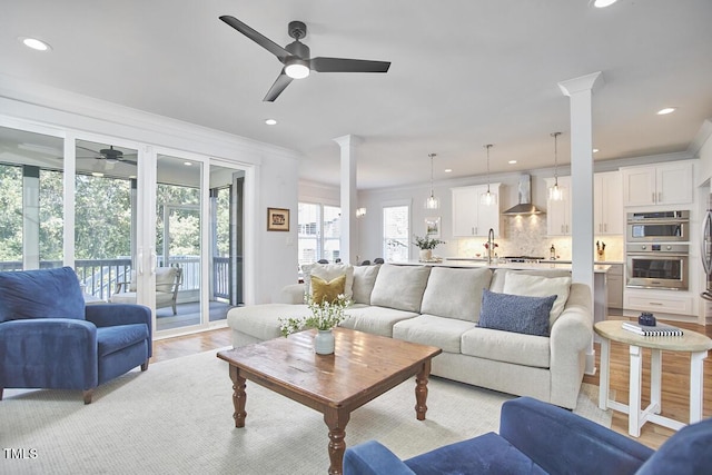 living room with light wood-style floors, recessed lighting, decorative columns, and crown molding