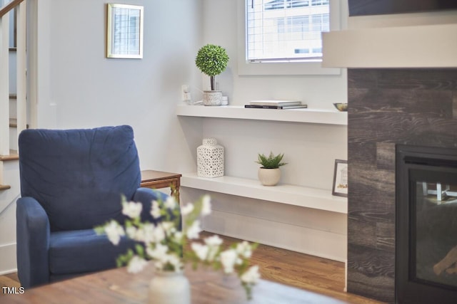 living area featuring wood finished floors and a glass covered fireplace