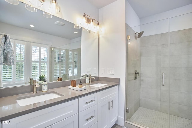 full bath featuring double vanity, a stall shower, a sink, and recessed lighting