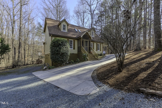 new england style home with driveway and a shingled roof