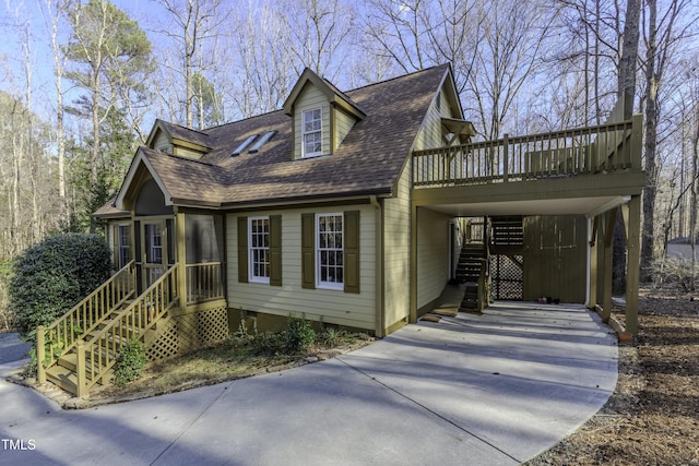 view of front facade with an attached carport, driveway, a wooden deck, roof with shingles, and stairs