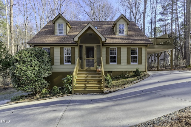 new england style home with an attached carport, roof with shingles, driveway, and crawl space