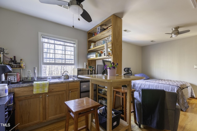 kitchen with light wood-style flooring, brown cabinetry, and ceiling fan