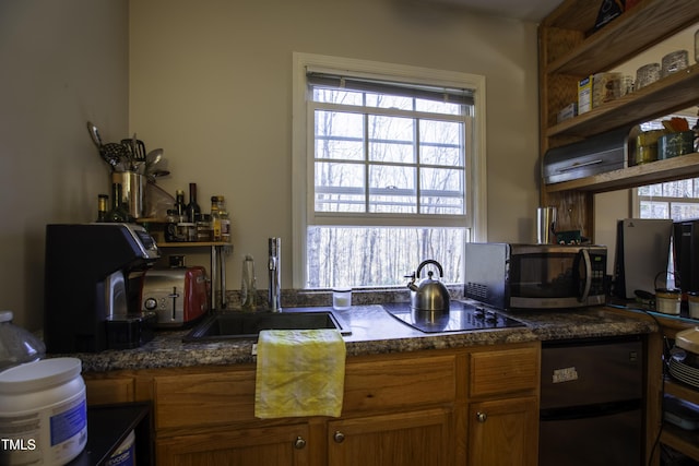 kitchen with a sink, stainless steel microwave, refrigerator, brown cabinetry, and black electric stovetop