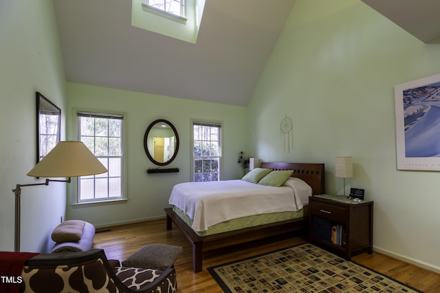 bedroom with wood finished floors, baseboards, and high vaulted ceiling