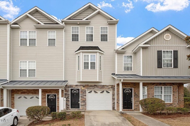 multi unit property with driveway, a standing seam roof, an attached garage, and brick siding