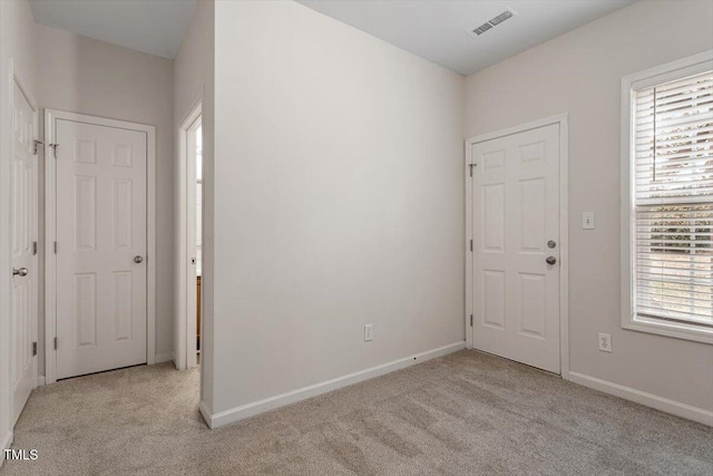 spare room featuring baseboards, visible vents, and light colored carpet