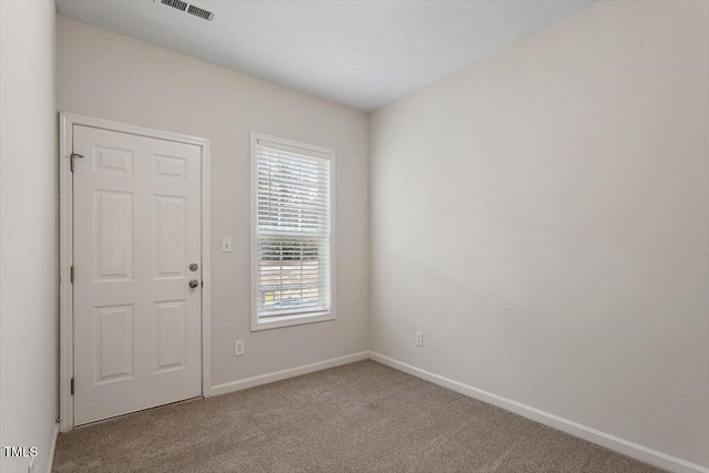 spare room featuring carpet, visible vents, and baseboards