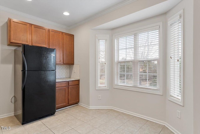 kitchen featuring crown molding, brown cabinetry, freestanding refrigerator, and decorative backsplash