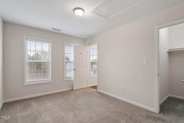 unfurnished bedroom with baseboards, visible vents, a walk in closet, carpet flooring, and a closet