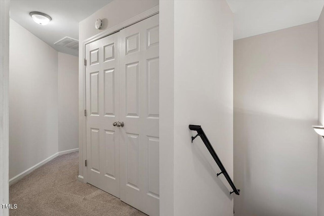 hallway featuring baseboards, visible vents, an upstairs landing, and light colored carpet