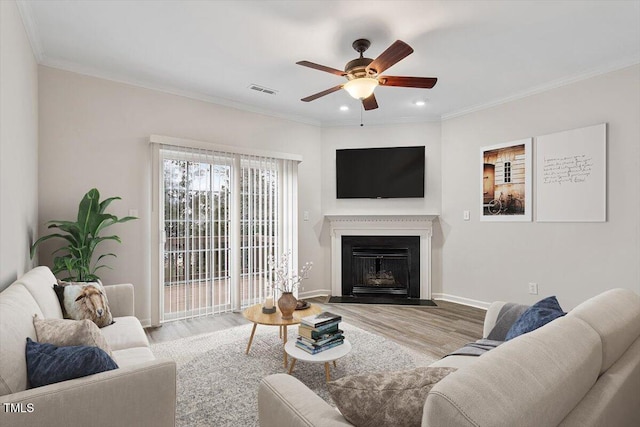 living area featuring ornamental molding, a fireplace, wood finished floors, and visible vents