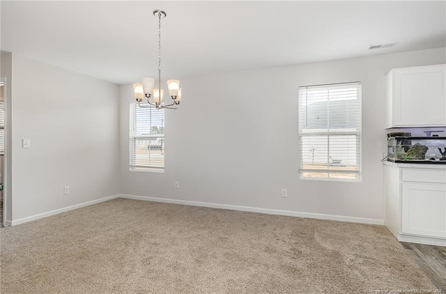 empty room with visible vents, baseboards, a chandelier, and light colored carpet