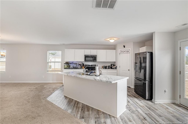 kitchen with appliances with stainless steel finishes, visible vents, baseboards, and white cabinetry