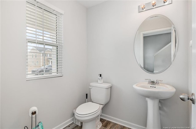 half bath featuring baseboards, toilet, and wood finished floors