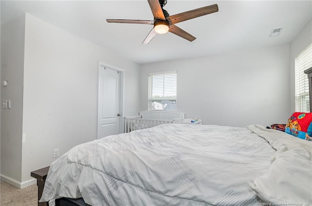 bedroom with light colored carpet, ceiling fan, visible vents, and baseboards