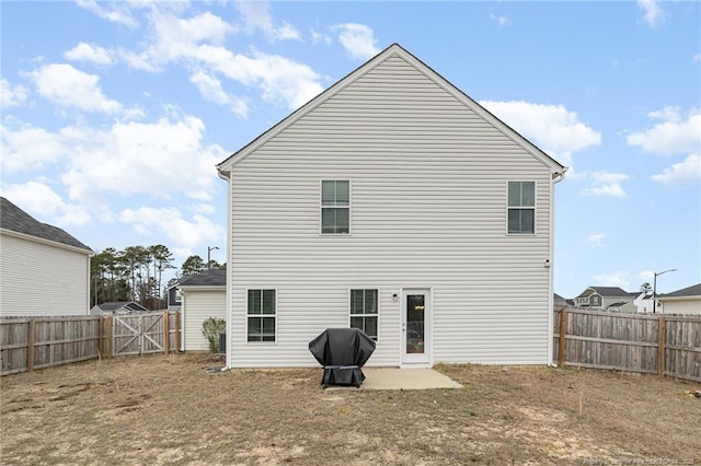 back of property with a patio, a fenced backyard, and a gate