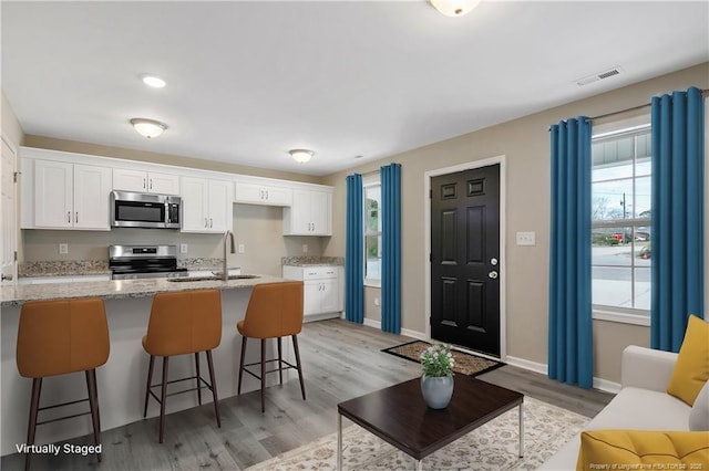 kitchen featuring a sink, plenty of natural light, appliances with stainless steel finishes, and white cabinets