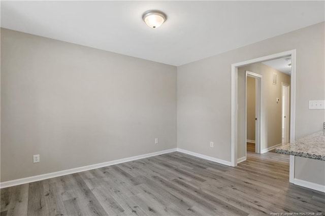 spare room featuring wood finished floors and baseboards