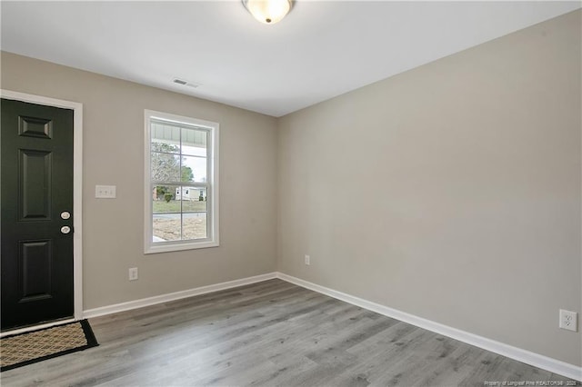 entryway with wood finished floors, baseboards, and visible vents