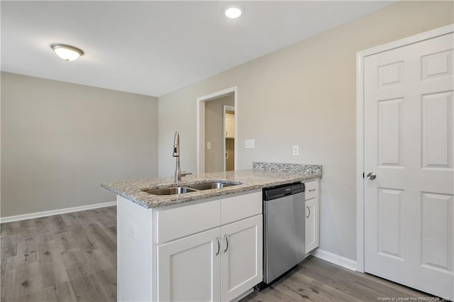 kitchen with a sink, light stone counters, stainless steel dishwasher, a peninsula, and white cabinets