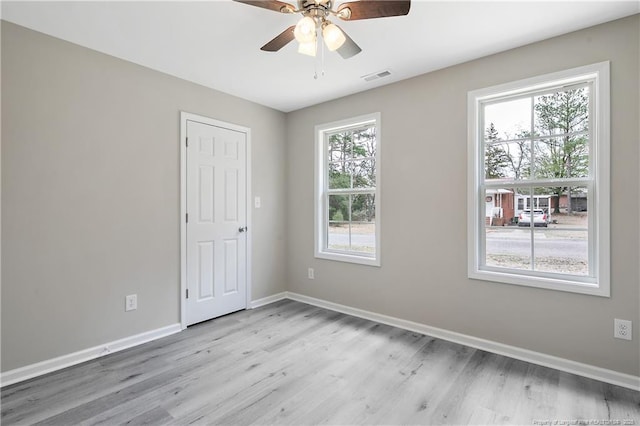 empty room with visible vents, baseboards, light wood-style flooring, and a ceiling fan