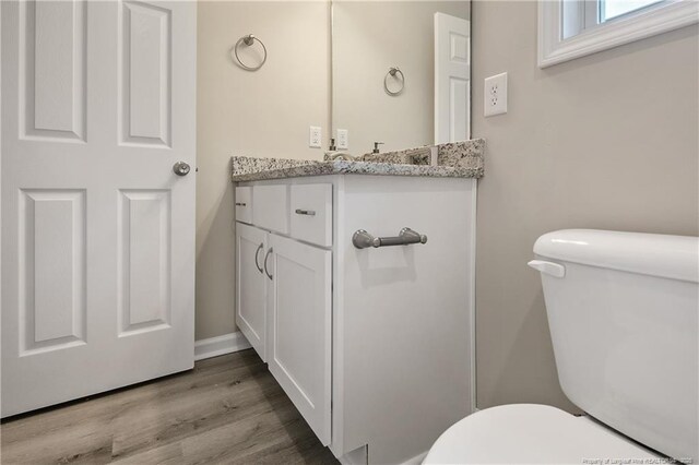 half bath with vanity, toilet, and wood finished floors