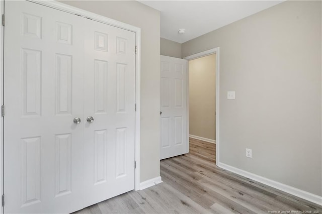 unfurnished bedroom with baseboards, a closet, and light wood-type flooring