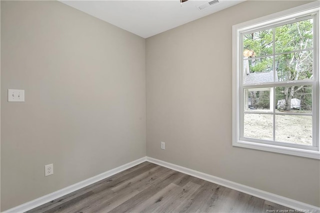 spare room featuring visible vents, baseboards, and wood finished floors