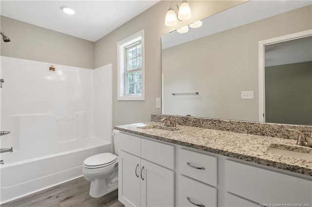 bathroom featuring a sink, toilet, wood finished floors, and double vanity