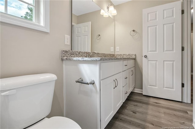 bathroom with toilet, wood finished floors, and vanity