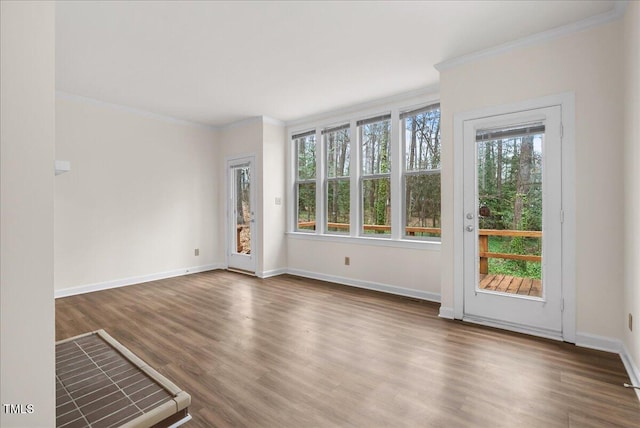 interior space with ornamental molding, baseboards, and wood finished floors