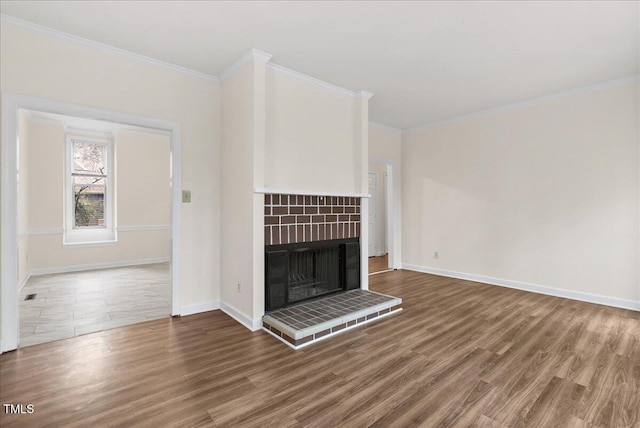 unfurnished living room with crown molding, baseboards, a fireplace with raised hearth, and wood finished floors