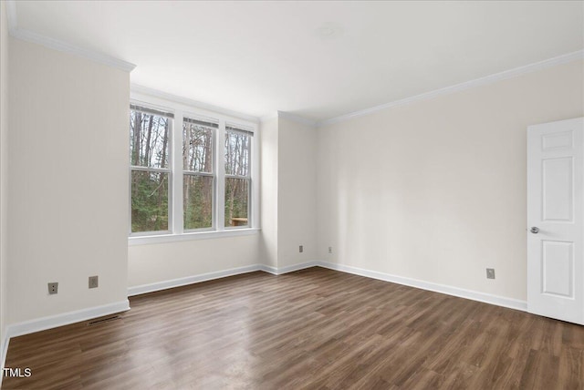 spare room with dark wood-style floors, ornamental molding, visible vents, and baseboards