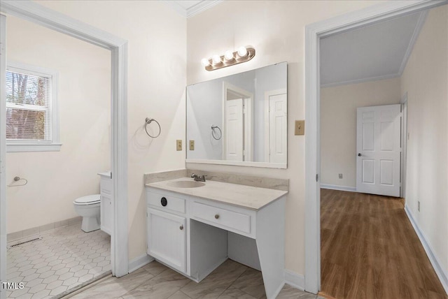 bathroom featuring baseboards, crown molding, vanity, and toilet