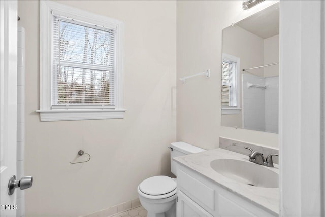 bathroom featuring toilet, walk in shower, a wealth of natural light, and vanity