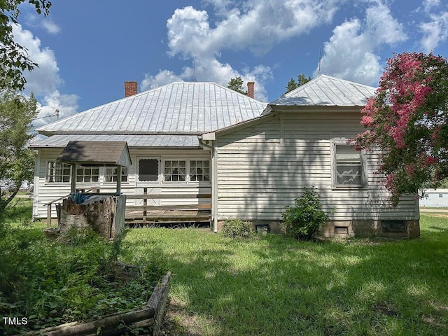 back of property featuring metal roof, a yard, and a chimney