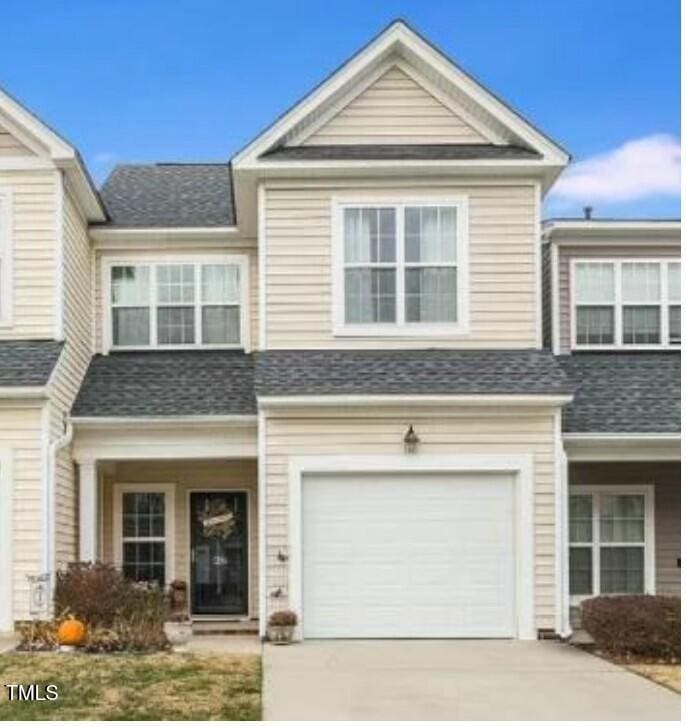 multi unit property featuring a garage, a shingled roof, and concrete driveway