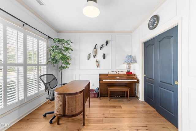 sitting room with crown molding, visible vents, a decorative wall, and light wood-style flooring