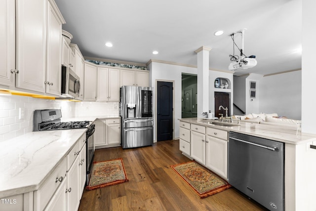 kitchen featuring stainless steel appliances, dark wood-type flooring, a sink, light stone countertops, and crown molding