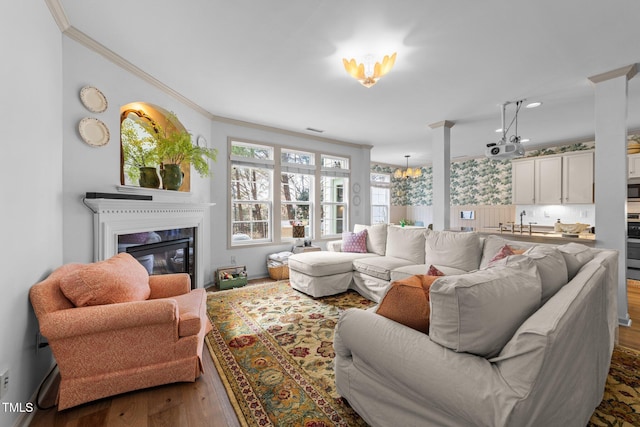 living room with wood finished floors, a notable chandelier, crown molding, and a premium fireplace