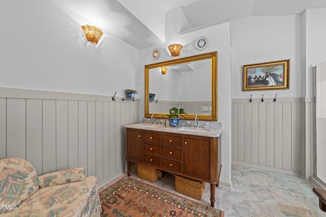 full bathroom featuring a wainscoted wall, marble finish floor, double vanity, and a sink