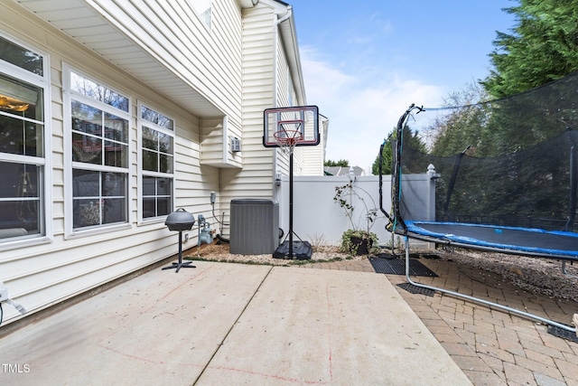 view of patio featuring a trampoline, cooling unit, and fence