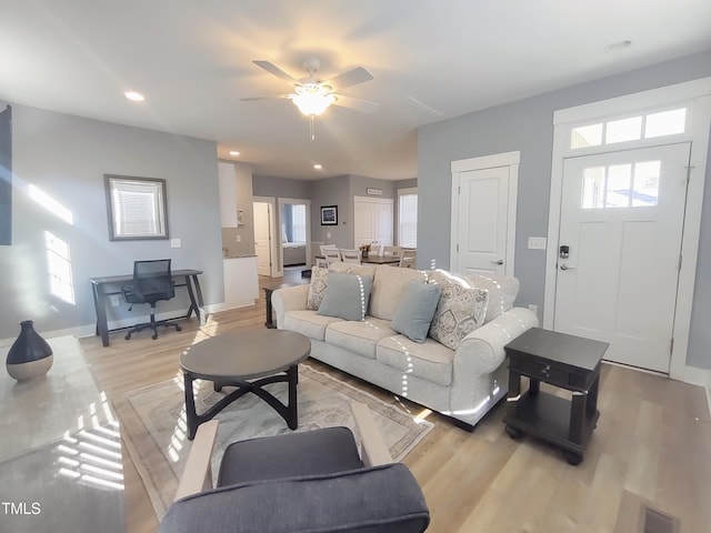 living area with a wealth of natural light, light wood-type flooring, visible vents, and baseboards